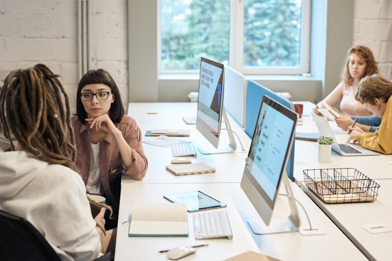 Cohort of marketers collaborating around a laptop